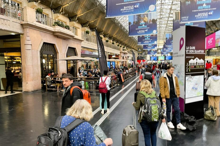 Travelers with backpacks and rolling luggage navigate a busy European train station, capturing the feel of moving through crowded terminals with carry-on bags.