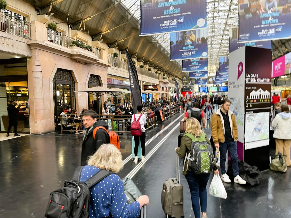 Travelers with backpacks and rolling luggage navigate a busy European train station, capturing the feel of moving through crowded terminals with carry-on bags.