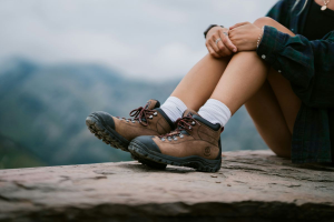 Day hiker resting with boots on a ledge, overlooking a mountain view
