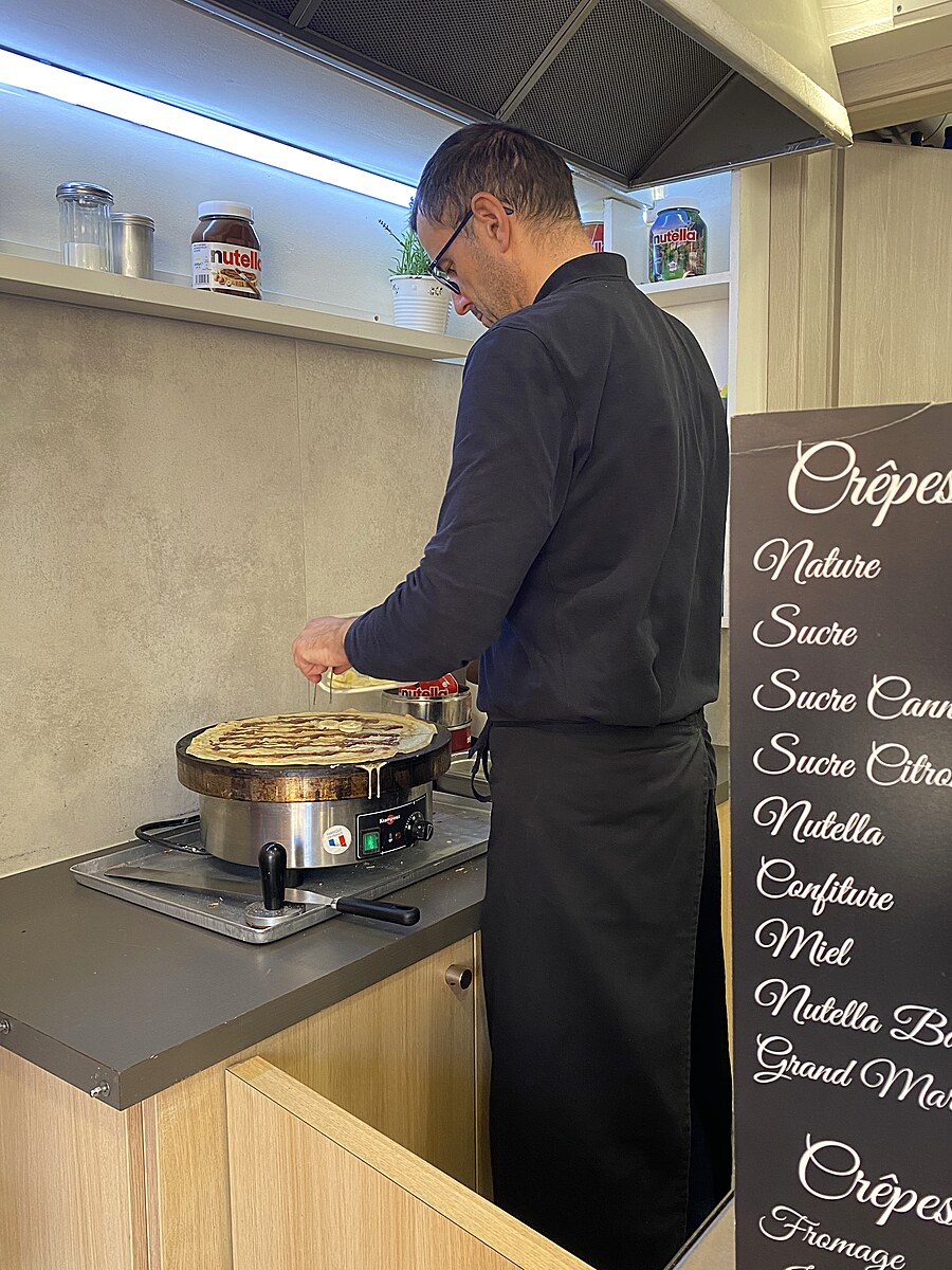 Cook preparing a fresh cr&ecirc;pe at a cr&ecirc;perie in Colmar, France.